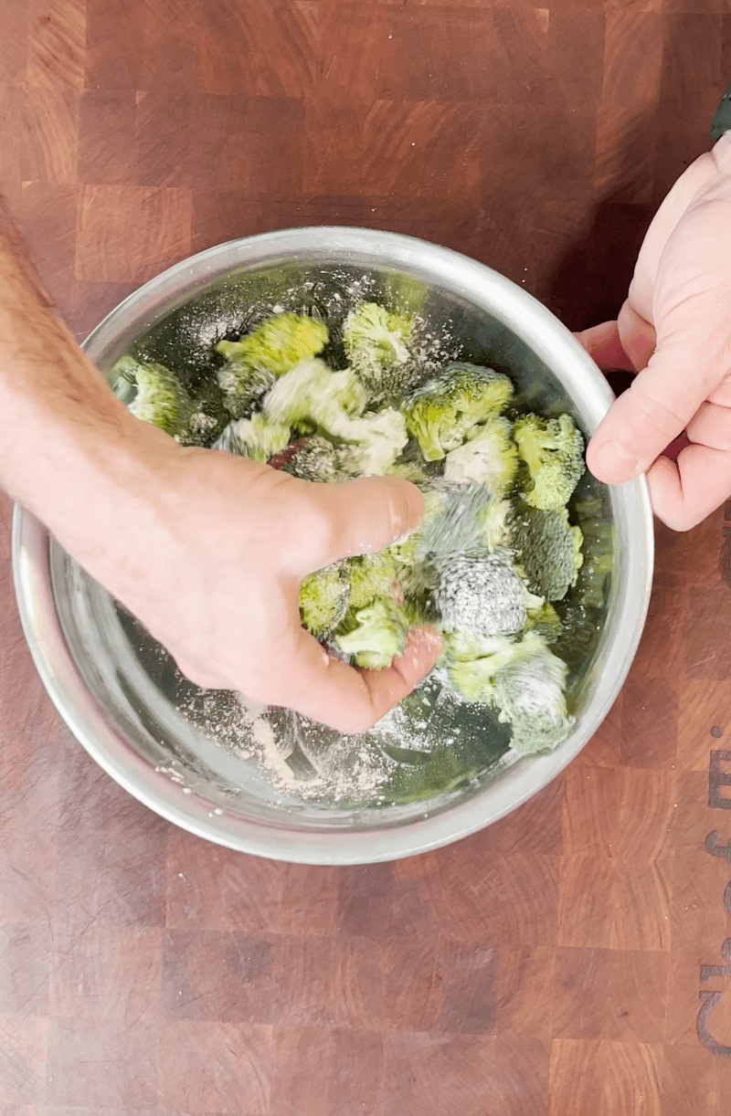 Mixing broccoli in seasoning.