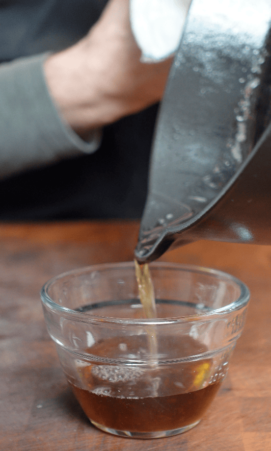 Bacon grease going into glass bowl.
