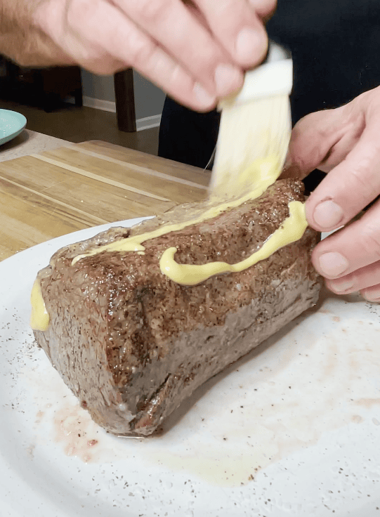 Dijon mustard on a cut of beef.