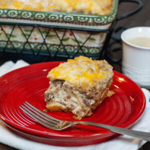 A slice of breakfast casserole on a red dish next to a cup of coffee.
