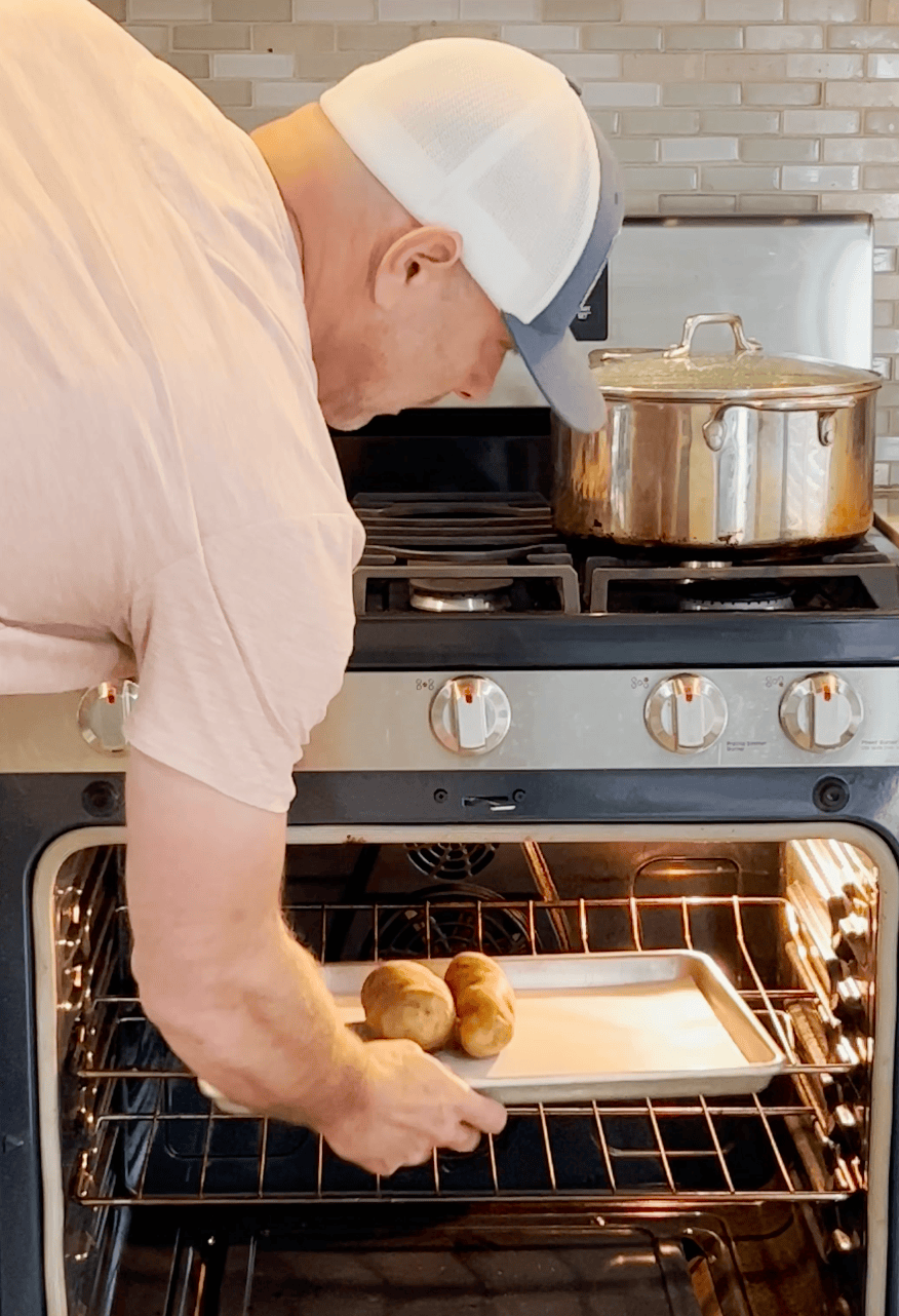 Tim putting potatoes into the oven to bake.