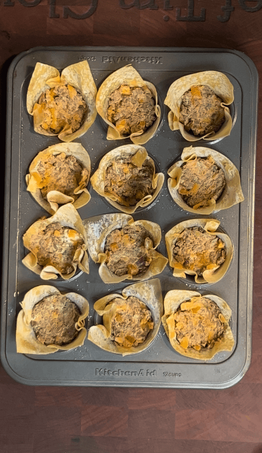 Meat in wontons in muffin pan.