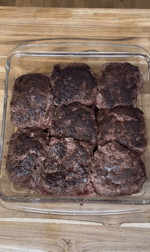 Hamburger patties in a baking dish.