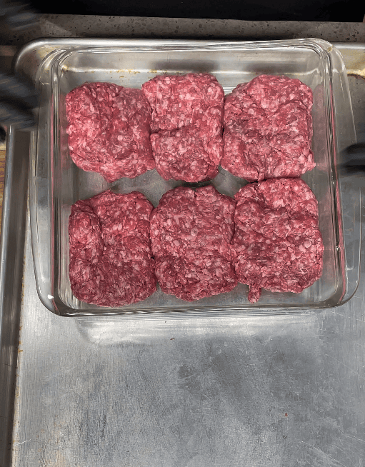 Burger patties going onto griddle.