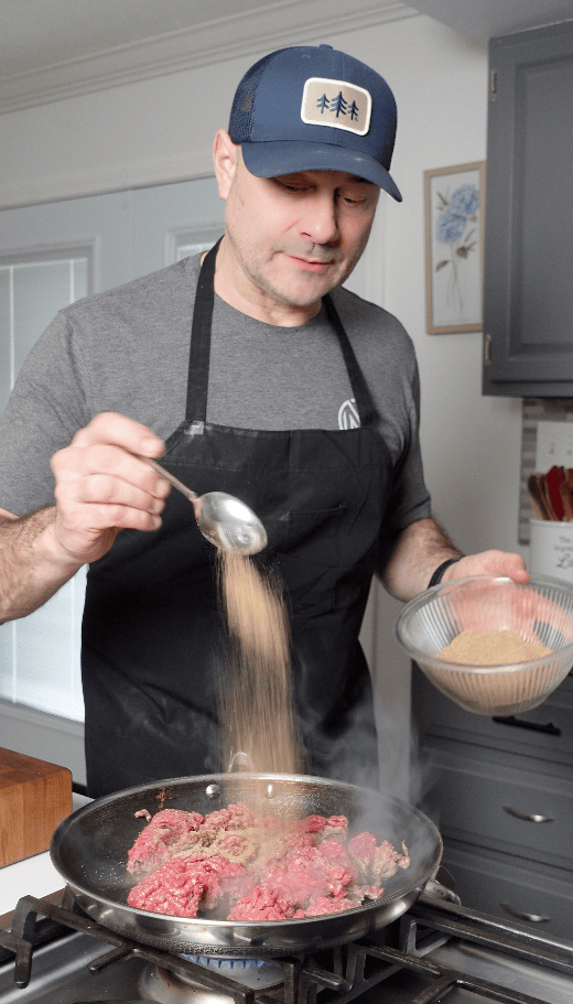 Taco seasoning going into a skillet.