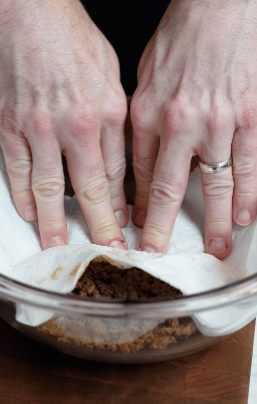 Ground meat being patted with paper towel.