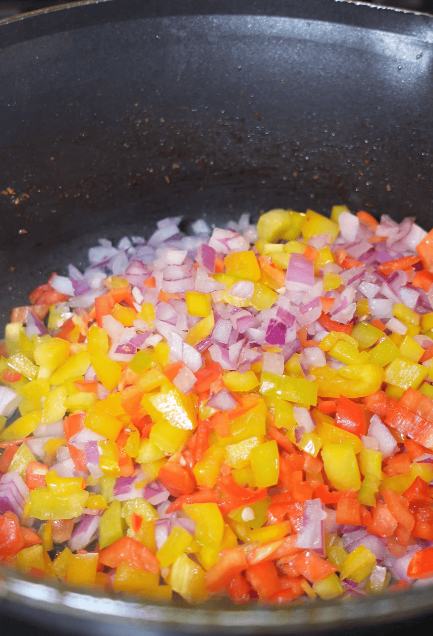 A skillet with peppers and onions cooking. 