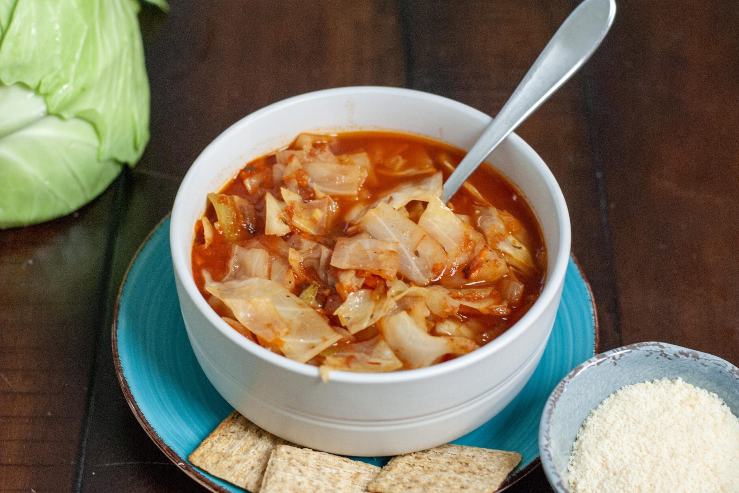 Cabbage soup in a bowl with parmesan cheese and crackers.