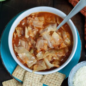Cabbage Soup next to shredded parmesan cheese and triscuits.