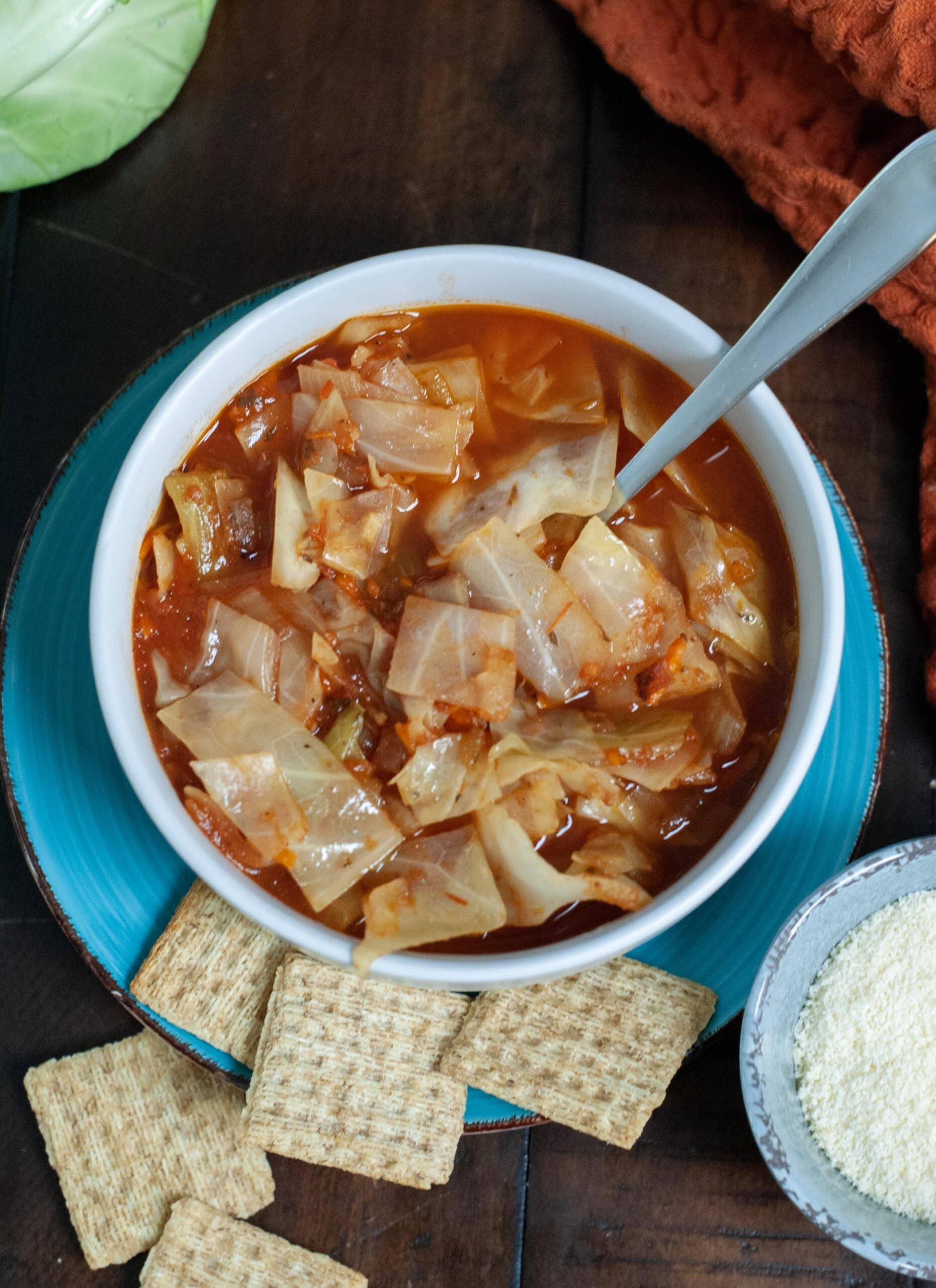 Cabbage Soup next to shredded parmesan cheese and triscuits.