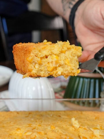 corn casserole on a spatula over a dish.