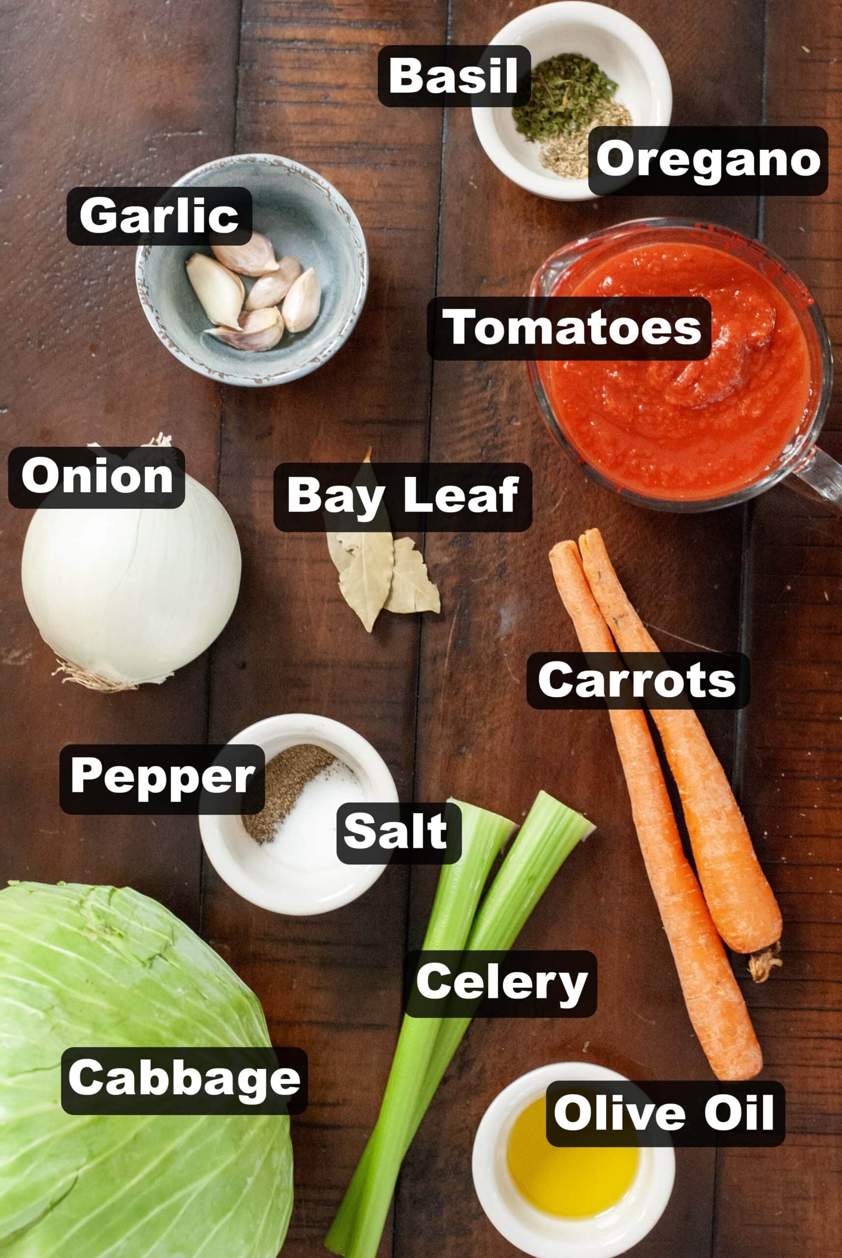 Ingredients measured out on a wooden surface for cabbage soup recipe.