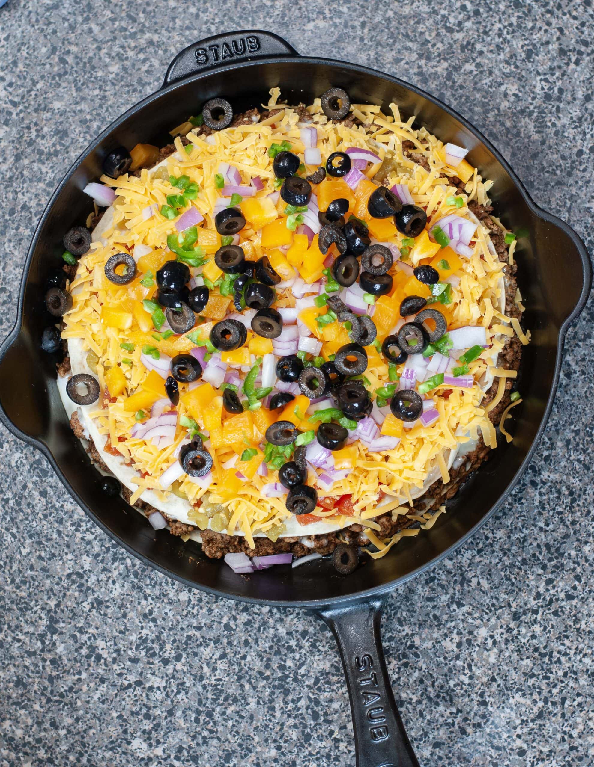 Mexican Pizza with toppings in a cast iron skillet.