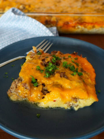A slice of sausage casserole on a blue plate.