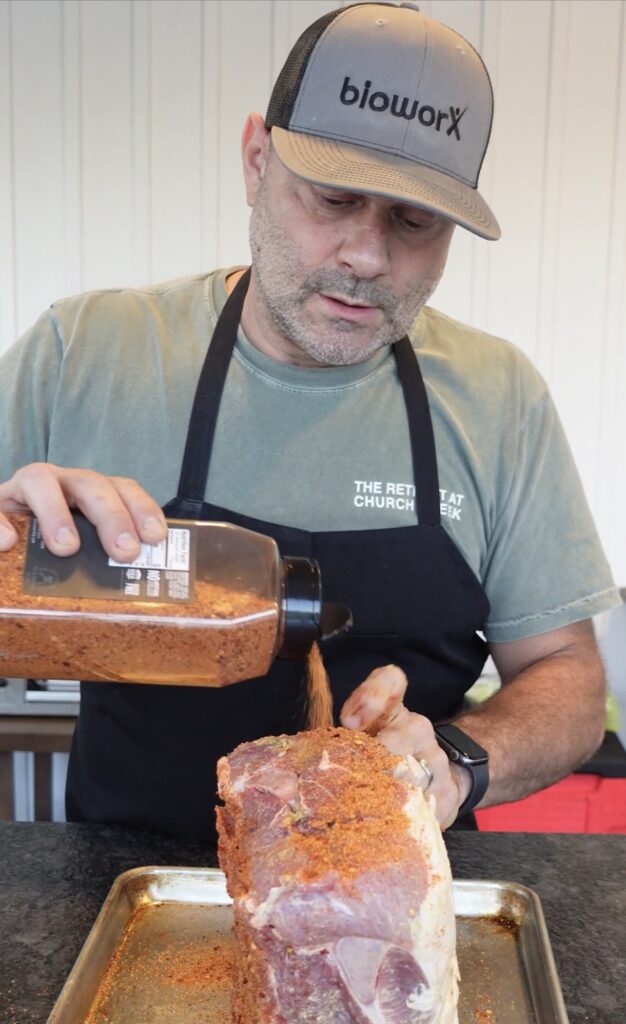 Seasoning a pork butt.
