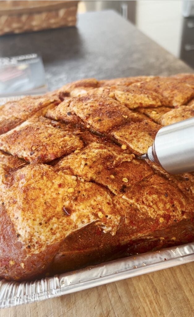 Injecting pork in a pan.