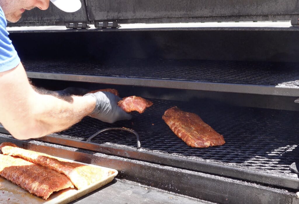 Tim placing ribs on the smoker.