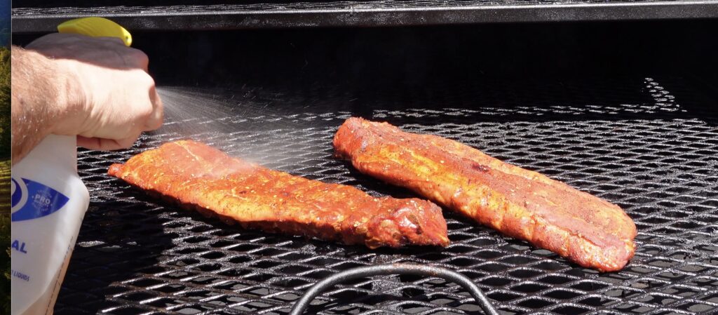 Spraying Smoked BBQ Pork Ribs on the smoker.