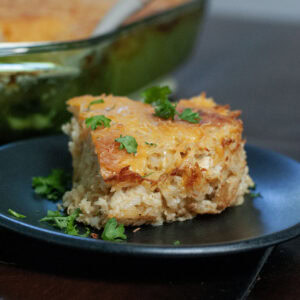 A slice of casserole with chicken and rice on a plate.