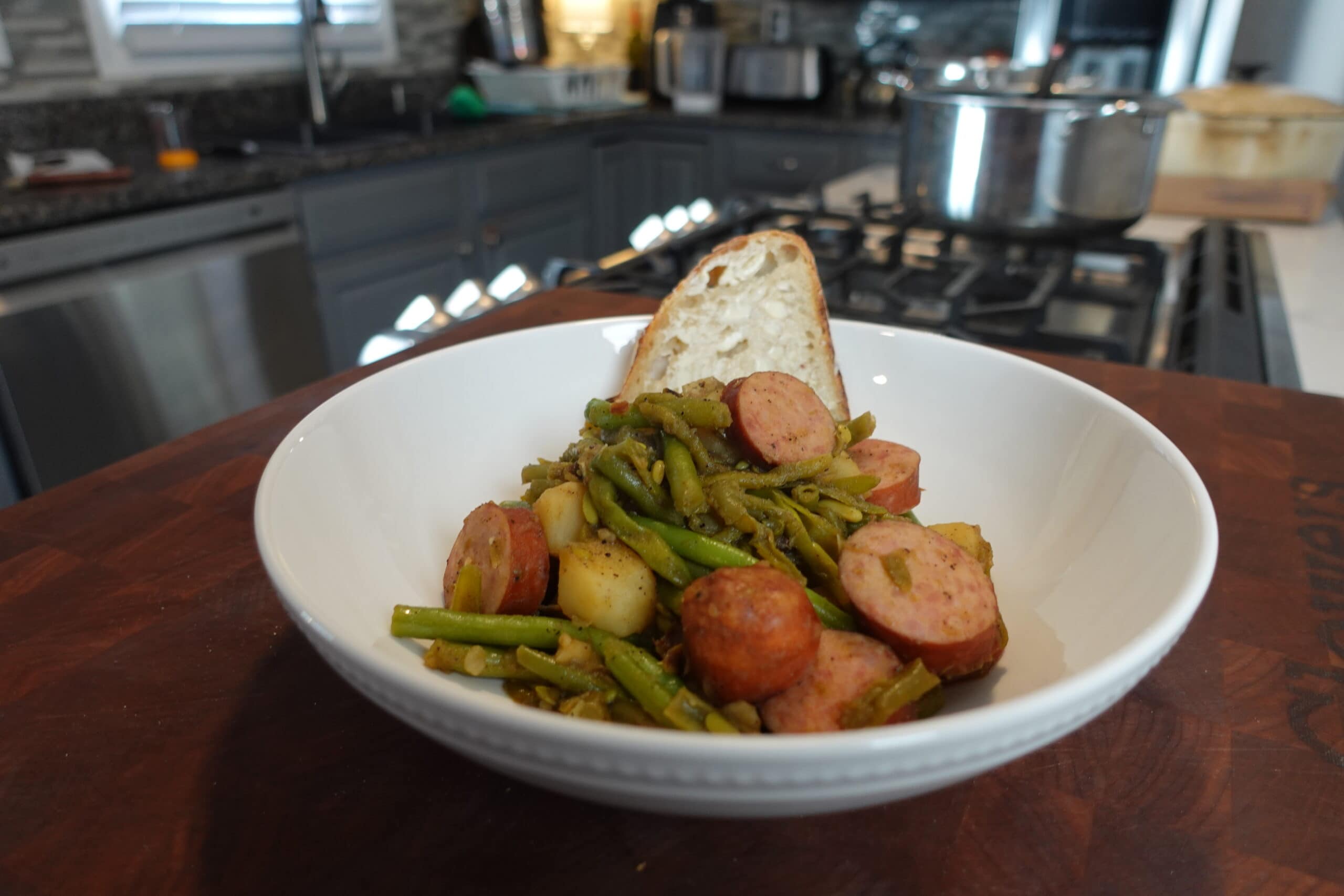 Kielbasa and Potatos in a bowl with bread.