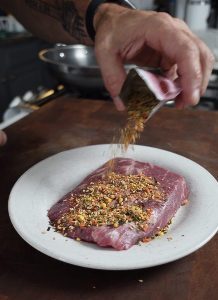Kimchi sprinkles on a slice of steak.