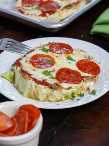 Cabbage pizza on a plate with pepperoni, cheese and parsley.