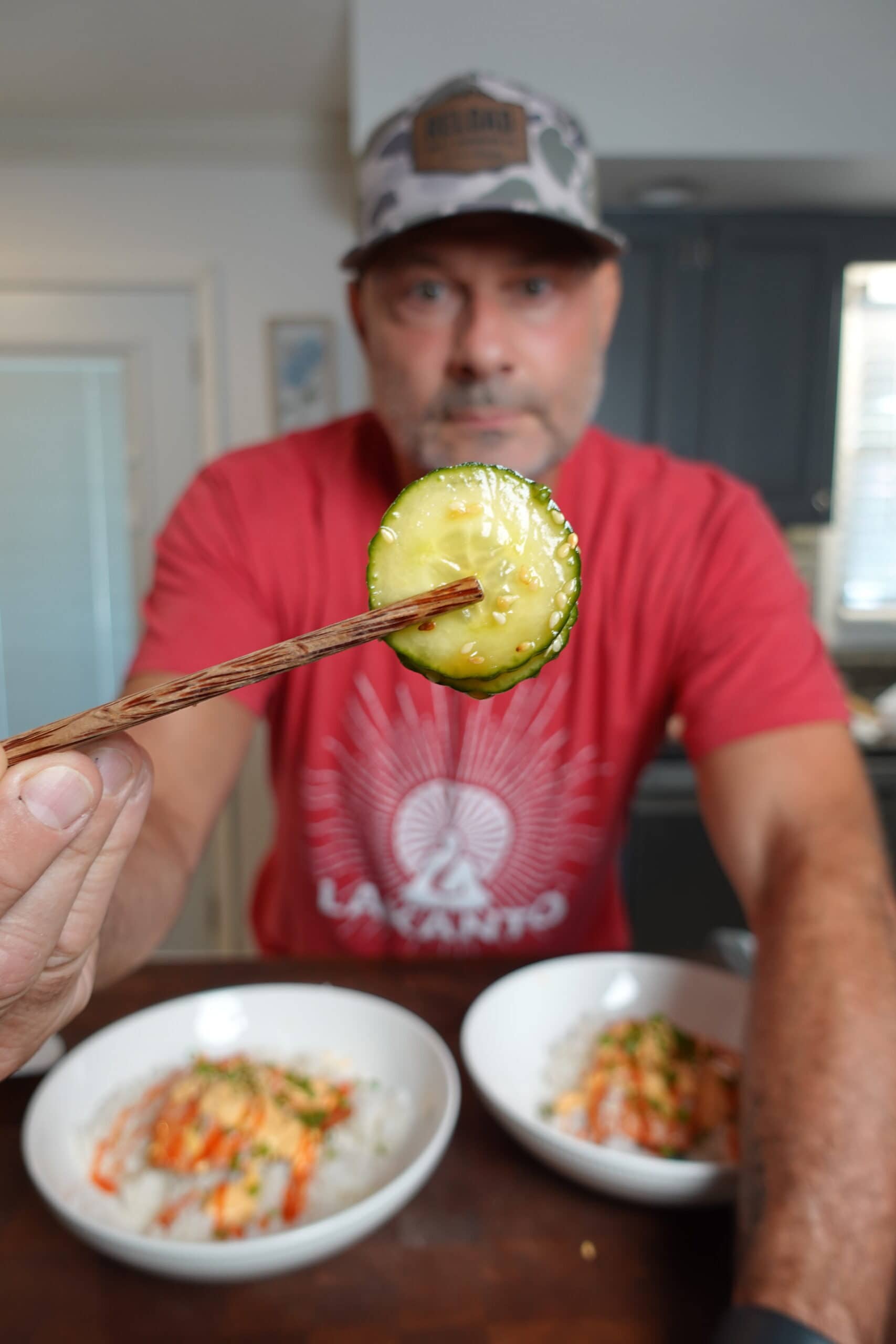 Holding up sliced cucumbers with chop sticks.