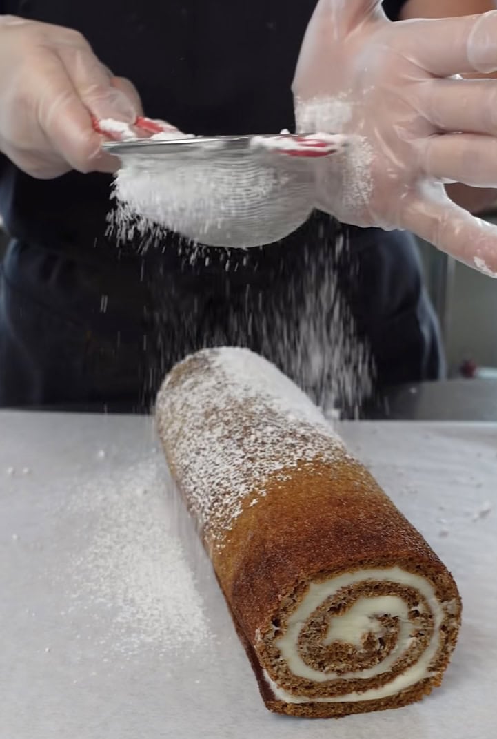 Dusting pumpkin roll with powdered sugar