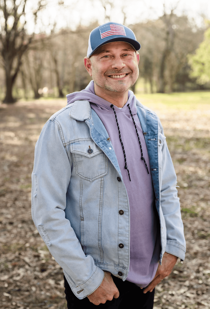 Tim standing in a field smiling.
