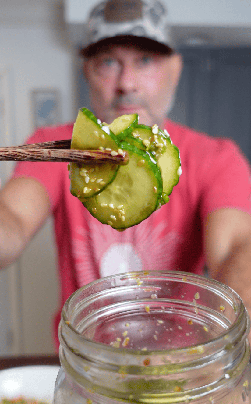 Asian cucumbers being held with chop sticks.