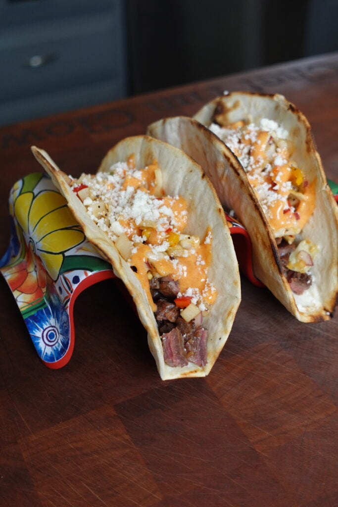 Steak tacos with crumbled cheese and sauce.