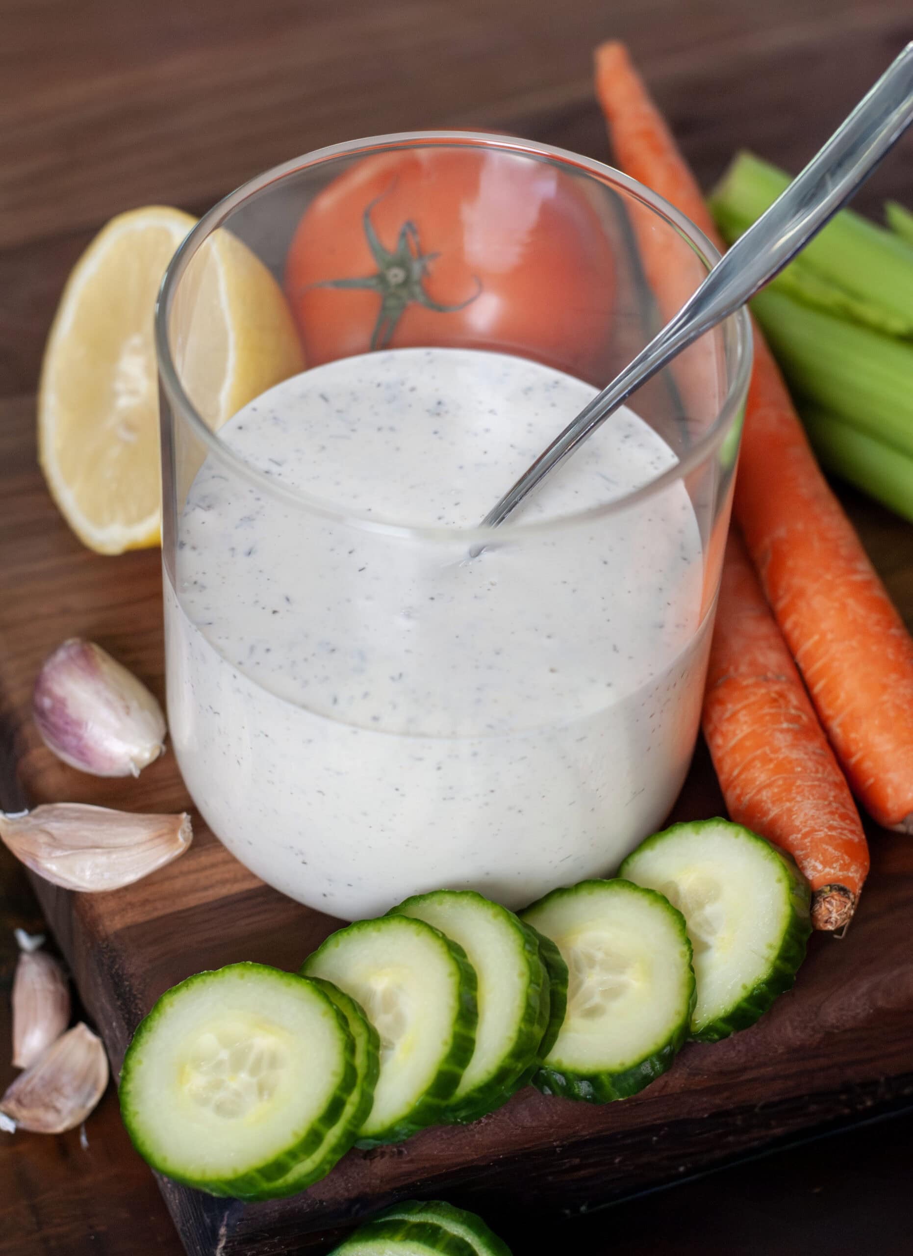 Ranch dressing in a jar next to cucumbers and carrots.