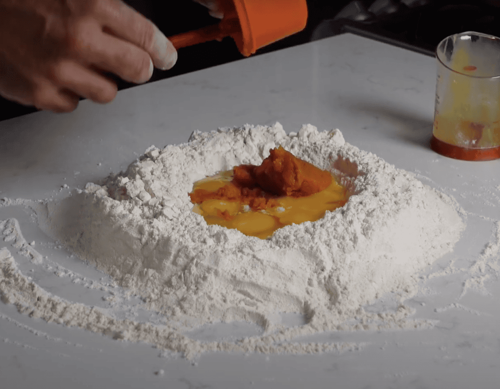 Pumpkin filling and eggs in a pile of flour.