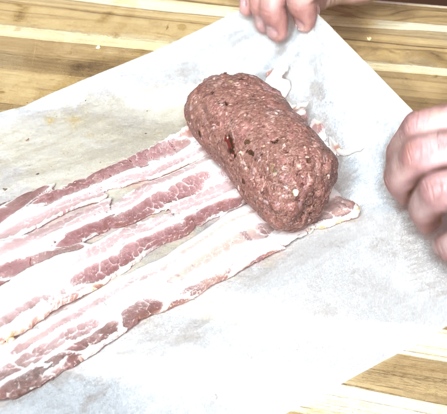 Ground meat being wrapped in bacon.