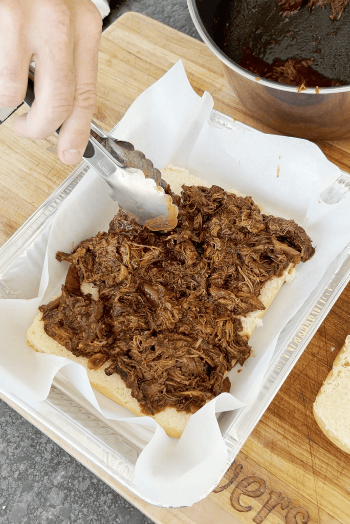 Birria meat going onto a slider.