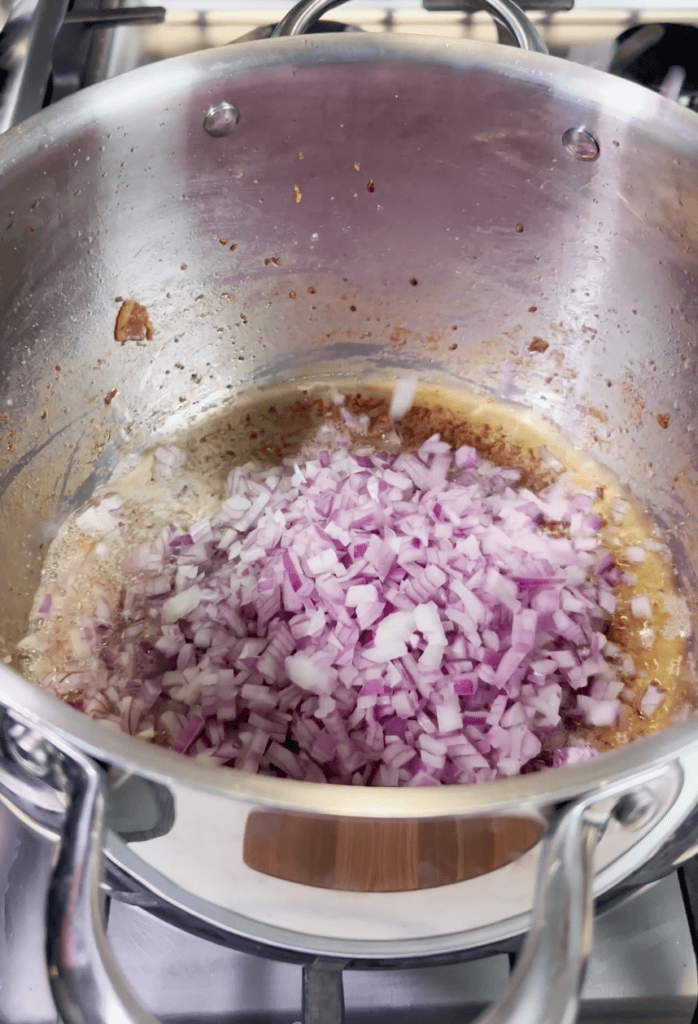 Red onions cooking in a pot.