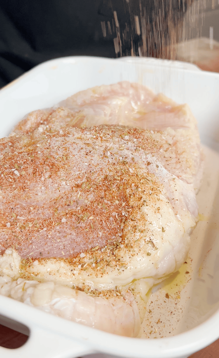 Seasoned turkey breast in a pan.