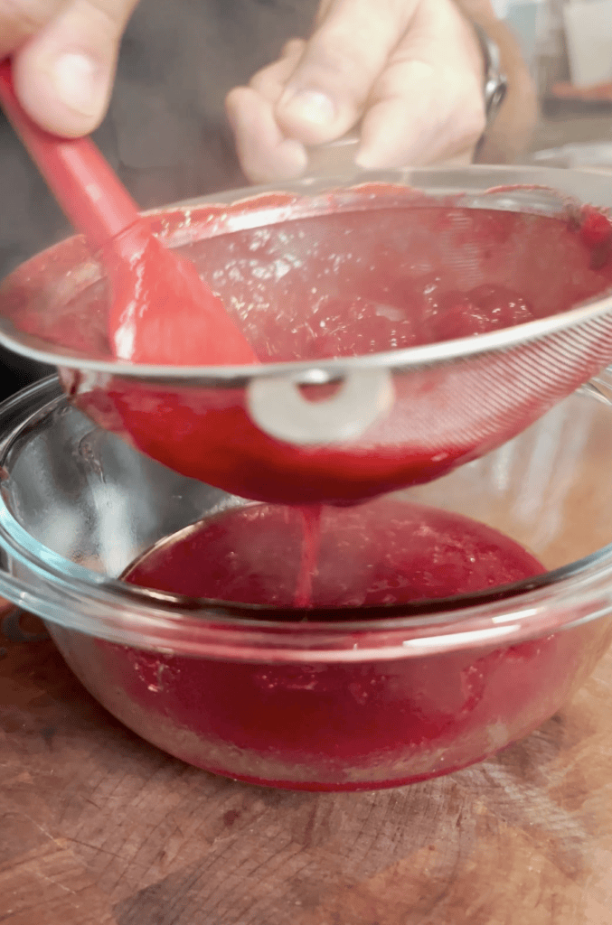 Cranberry sauce being strained into a bowl.