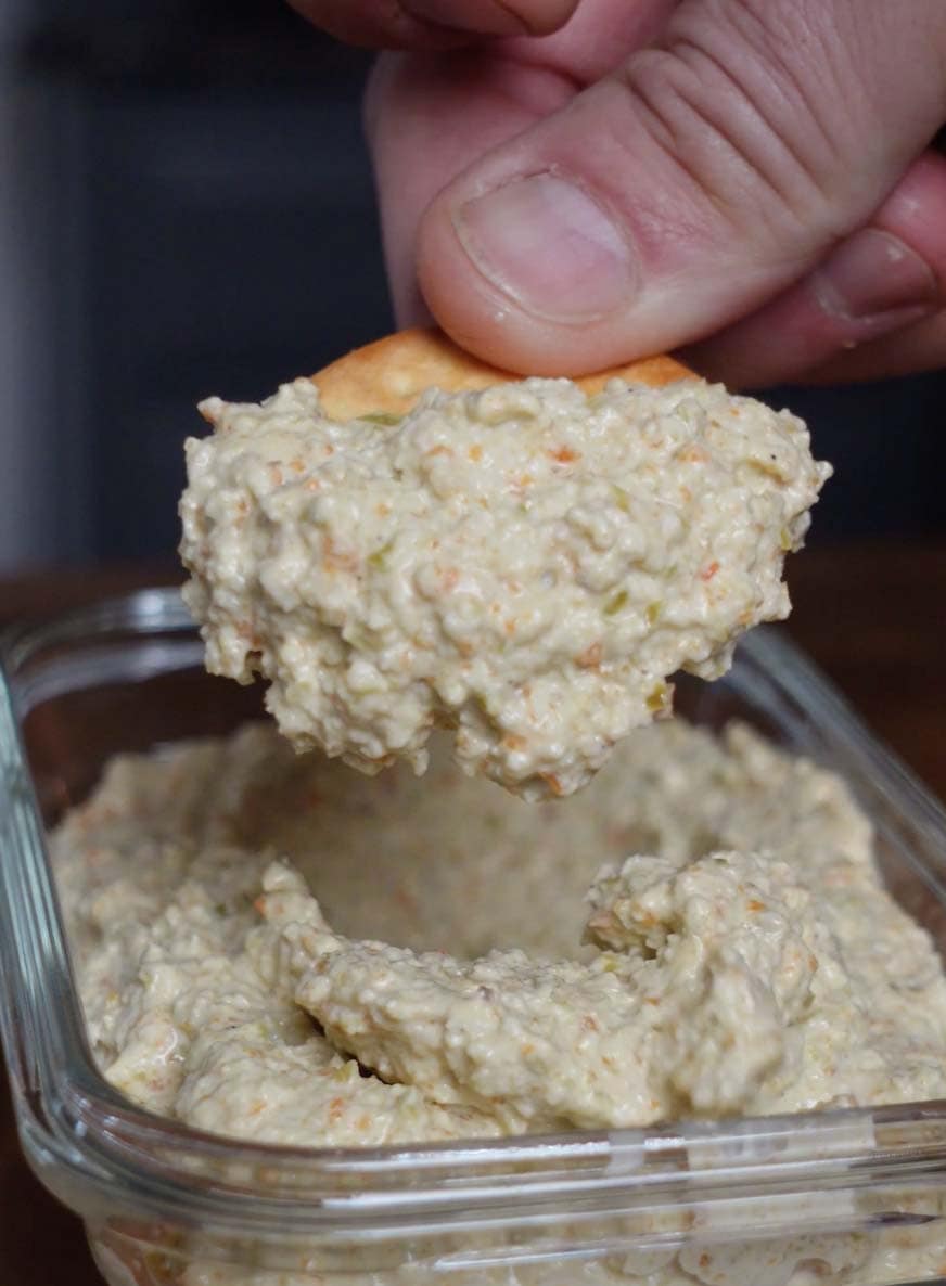 A pretzel scooping olive dip.