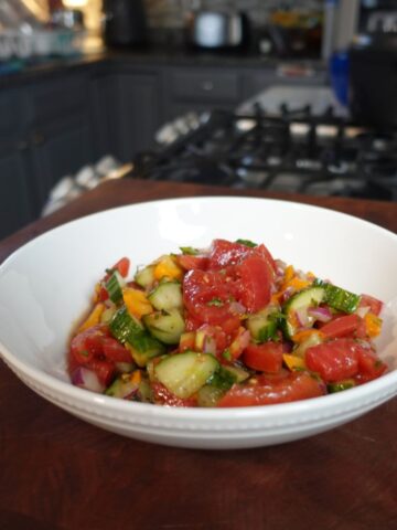 Tomatoes and cucumbers in a bowl with dressing.
