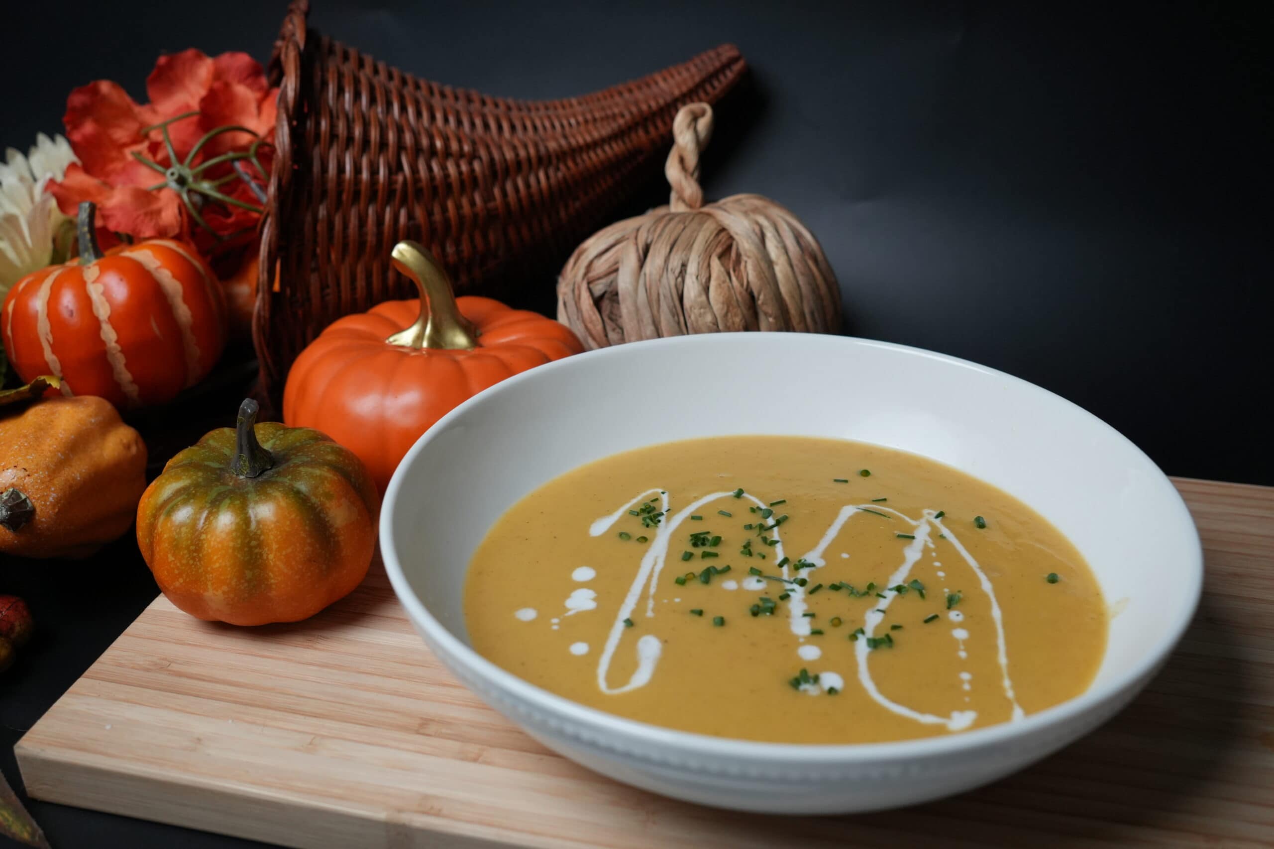 A bowl of pumpkin Soup surrounded by pumpkins.