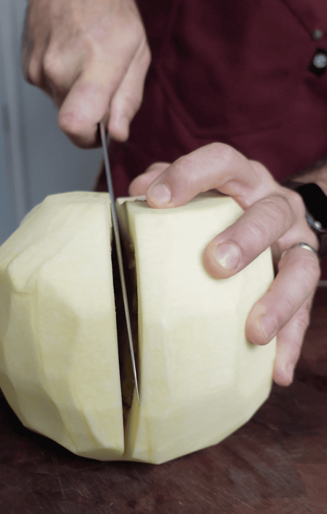 Cutting a pumpkin into chunks.