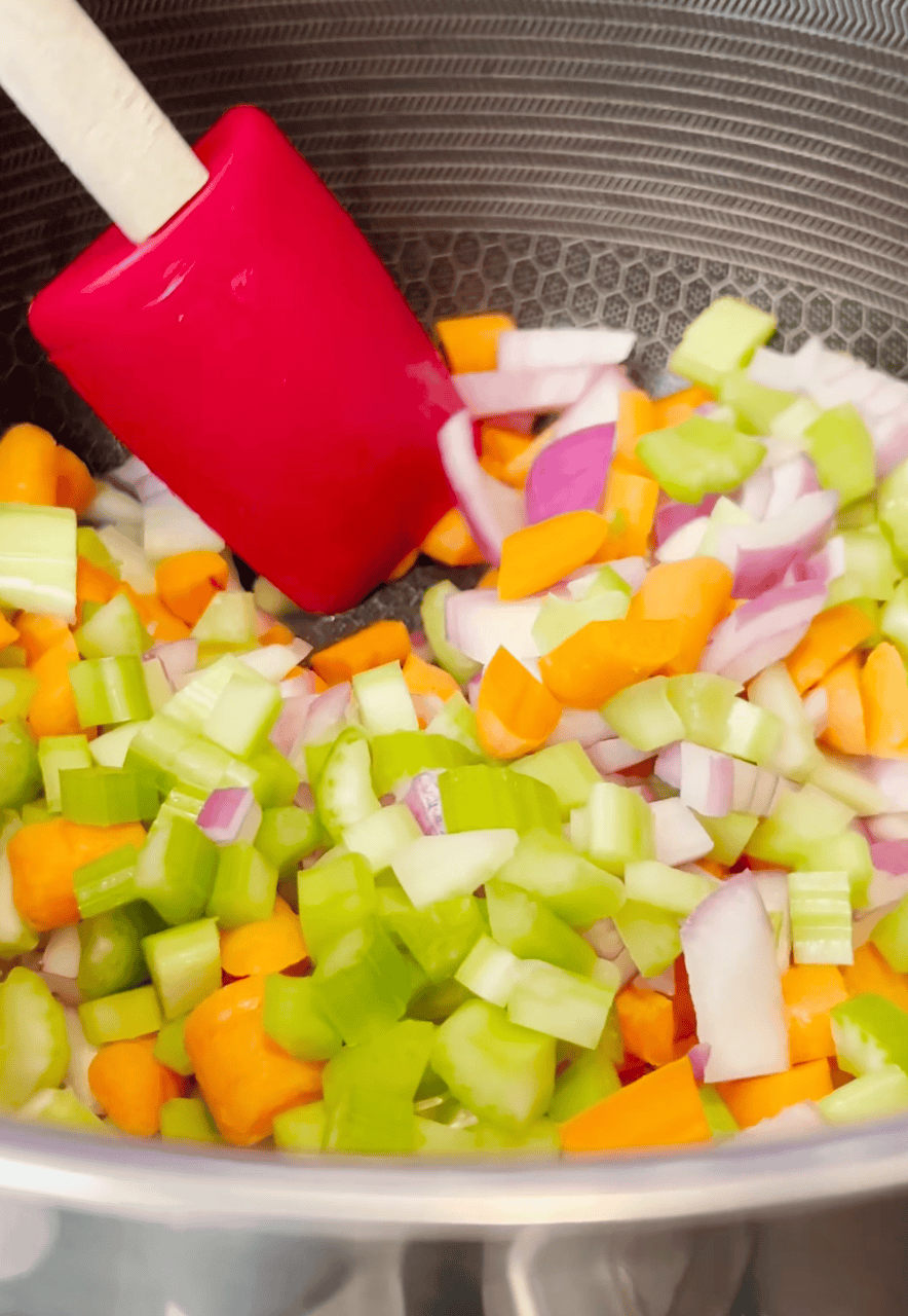 Celery, carrots and onion sautéing in a pot.