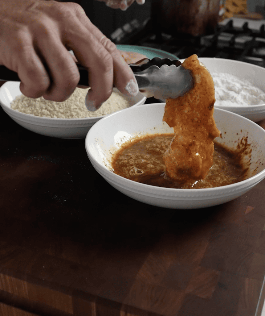 Chicken breast going into a dredge.