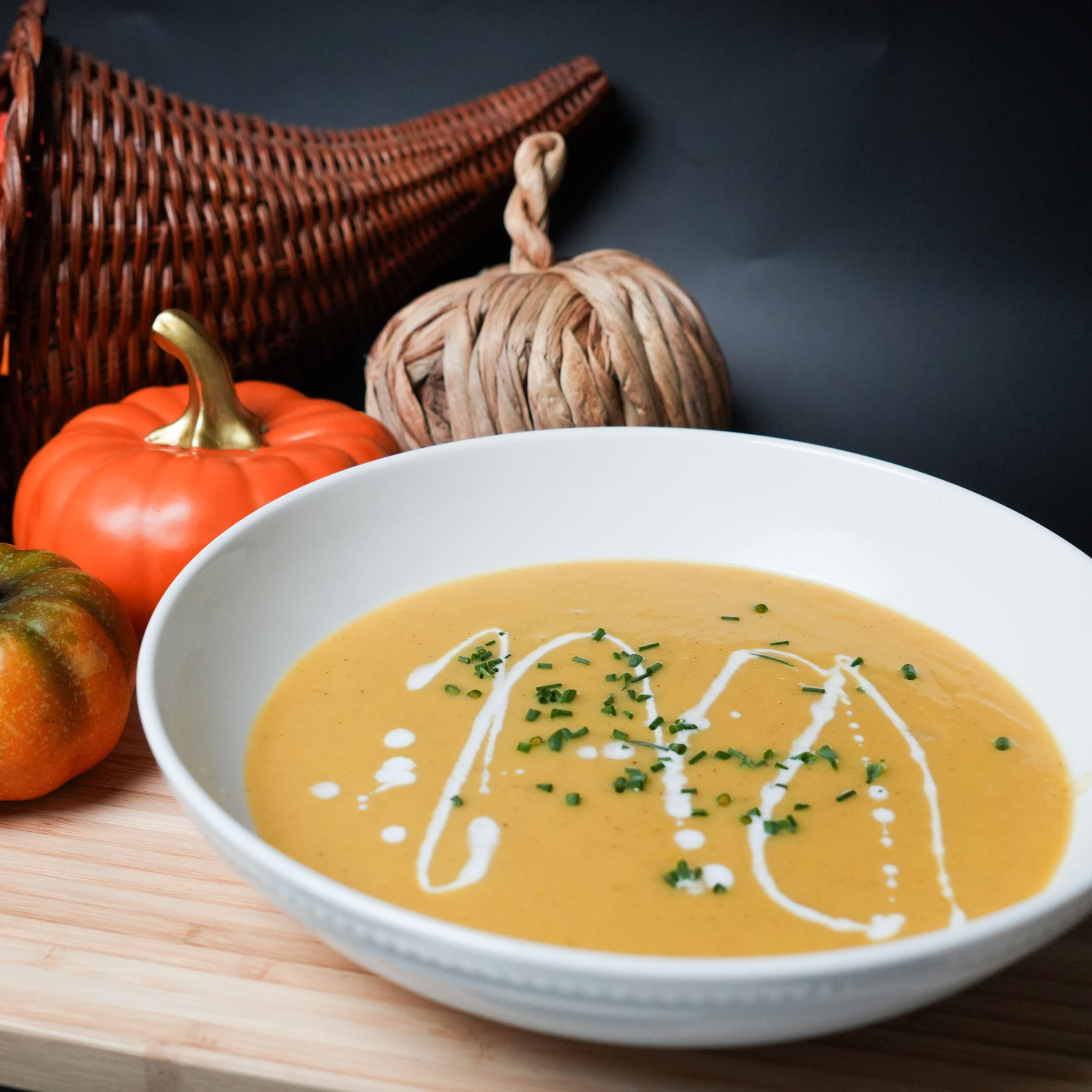 A bowl of pumpkin soup surrounded by decorative pumpkins.