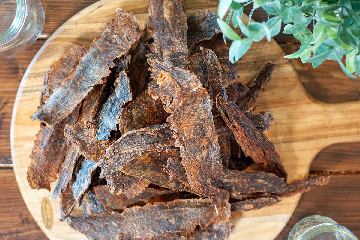 Homemade beef jerky on a wooden serving platter.