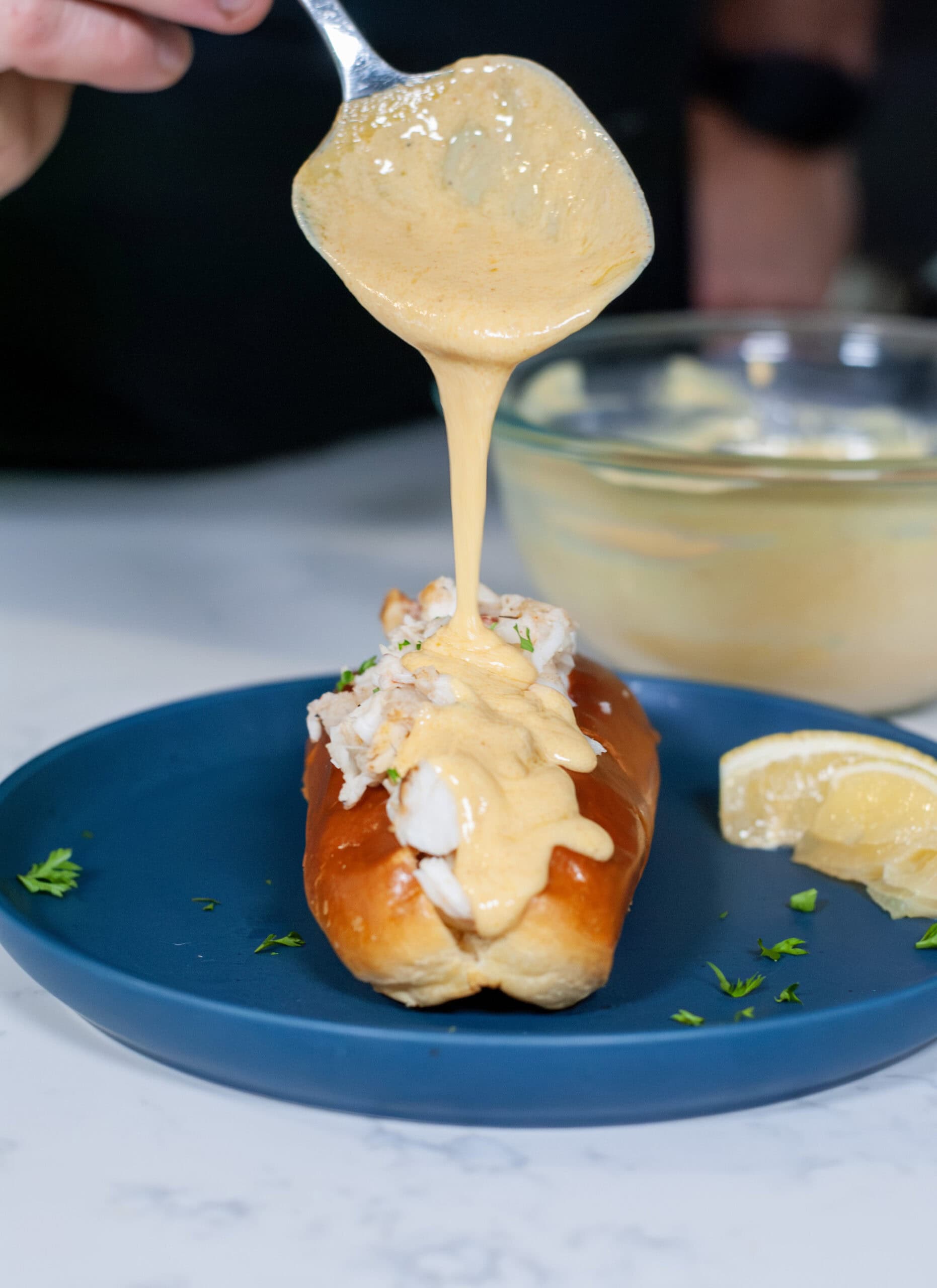 Beurre Blanc Sauce pouring over a lobster roll.