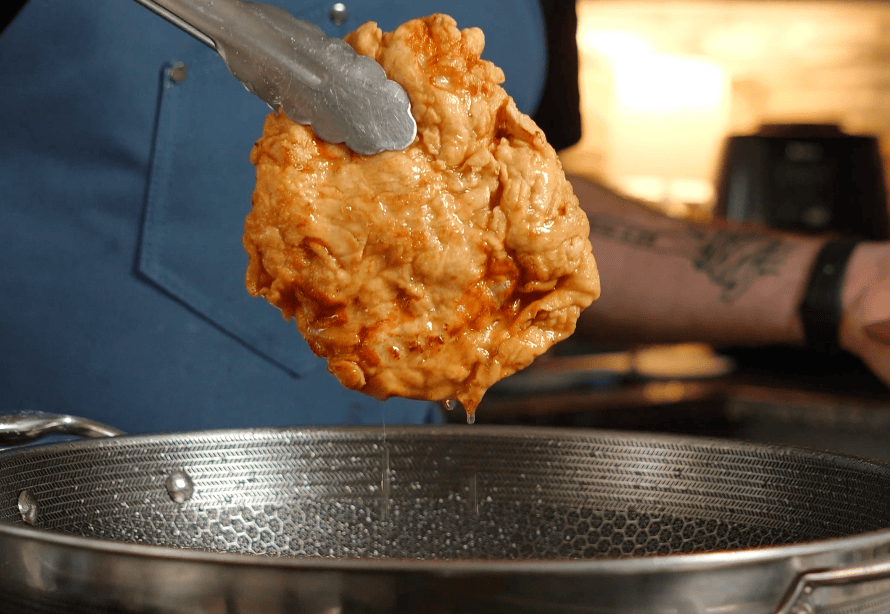 Fried chicken coming out of a pot.