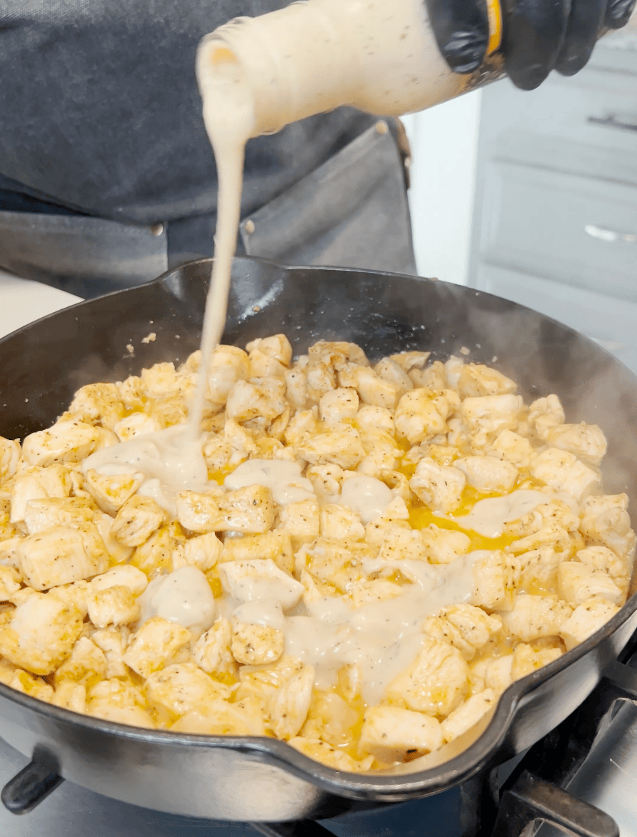 Garlic going onto chicken in a skillet.