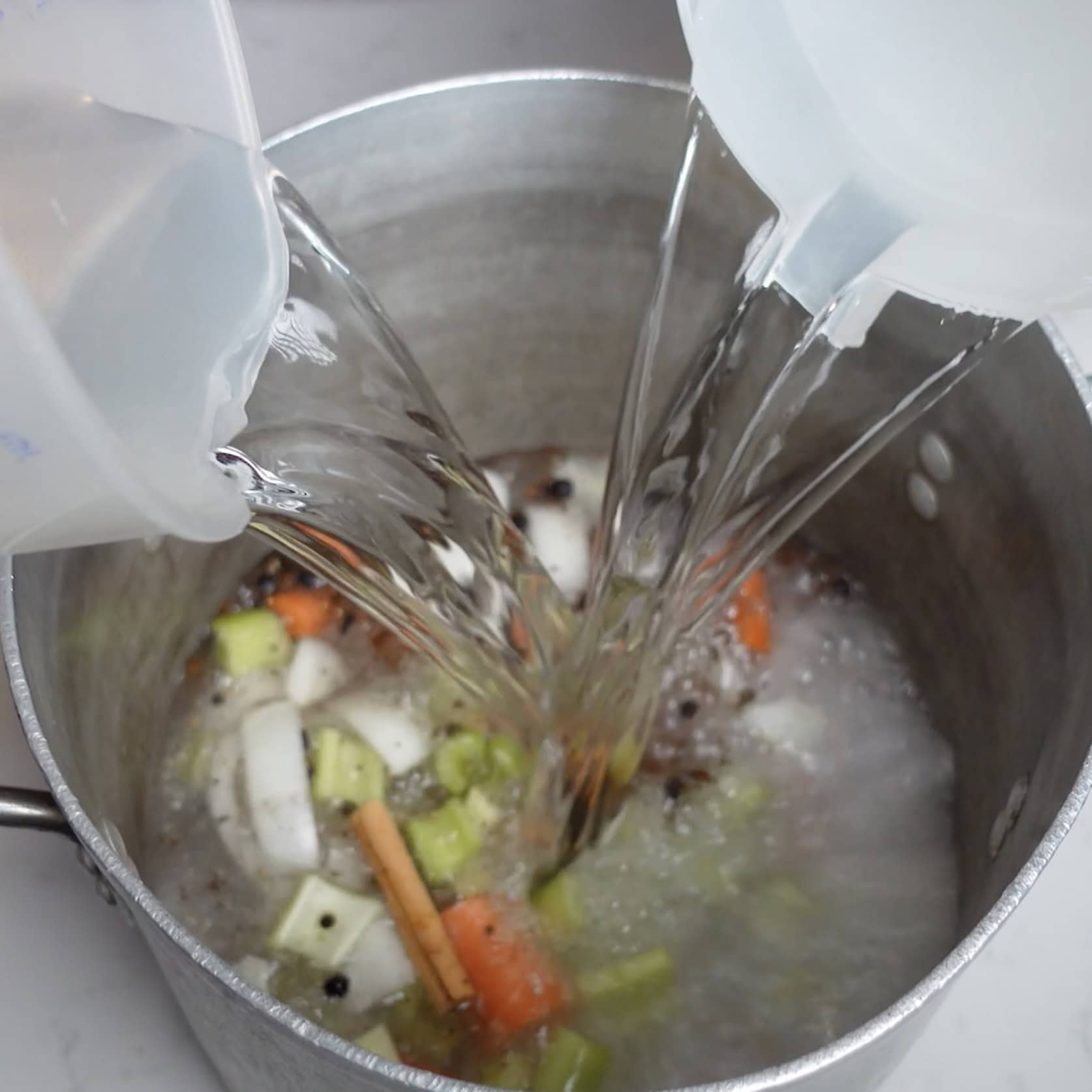 Water being poured over vegetables to make brine.
